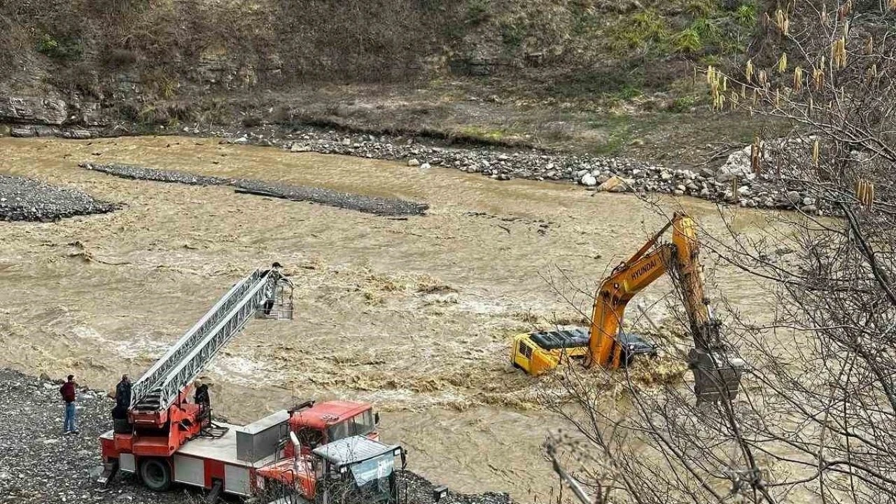 Çayın debisi yükselince iş makinesinin üzerinde mahsur kaldı