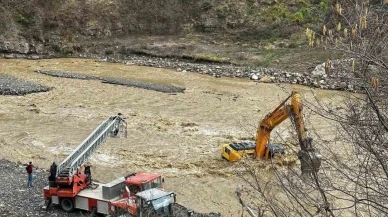 Çayın debisi yükselince iş makinesinin üzerinde mahsur kaldı