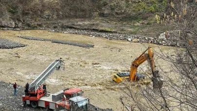 Çayın debisi yükselince iş makinesinin üzerinde mahsur kaldı
