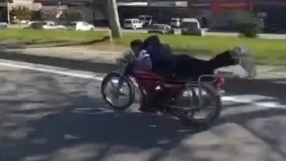 Plakasız motosiklet sürücüsü ellerini bırakıp motorun üzerine yatarak ilerledi